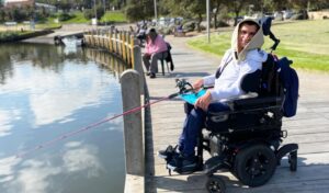 A man in a wheelchair is holding a fishing rod.